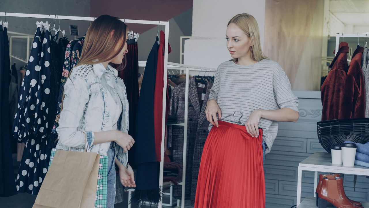 Two women shopping for clothes in a stylish boutique.